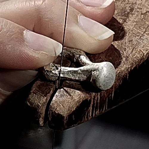 Jewellery maker shaping handcrafted silver jewellery in workshop