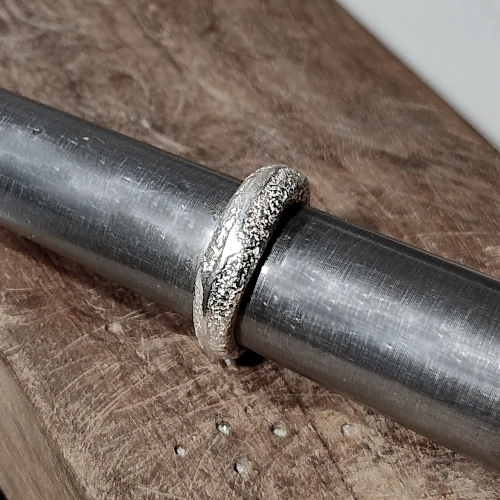 Jewellery making process showing artisan shaping silver by hand
